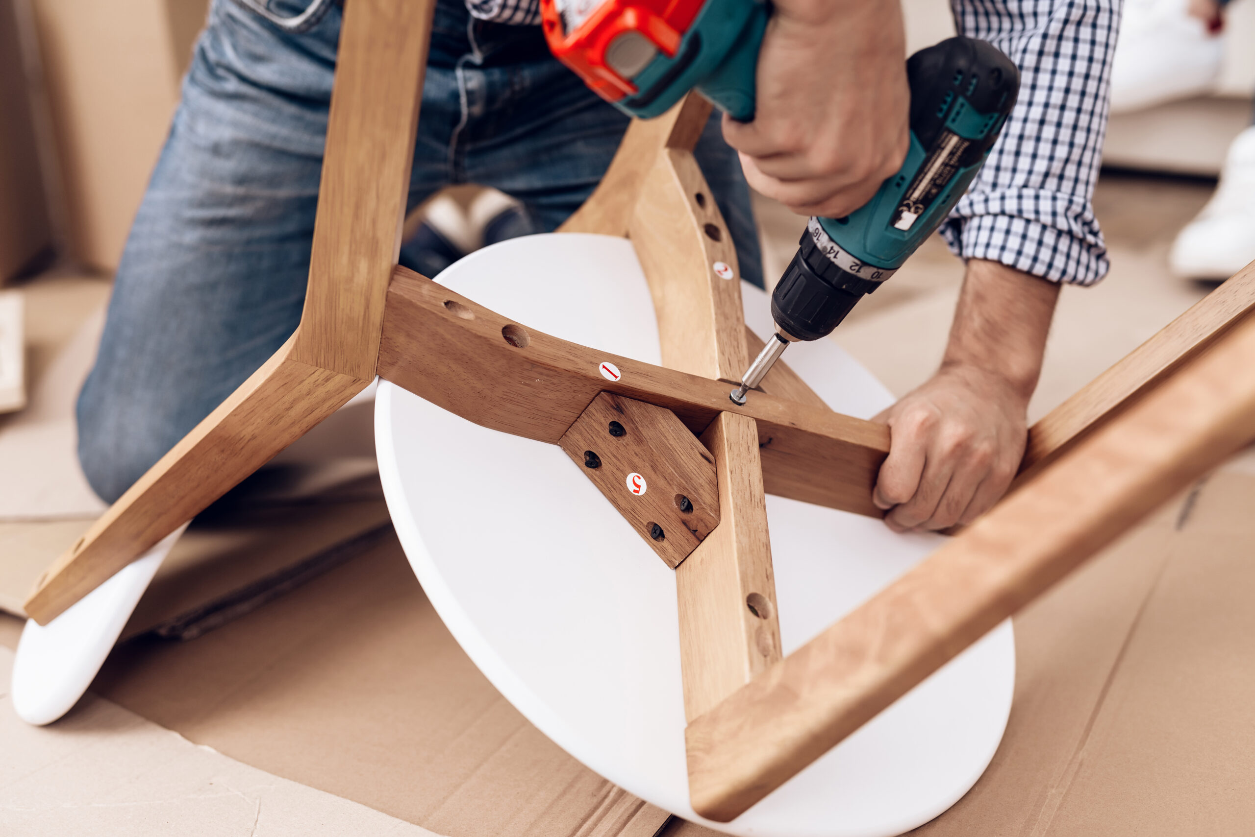 A handyman is assembling a chair, carefully joining its parts together. A handyman is assembling a chair, carefully joining its parts together.